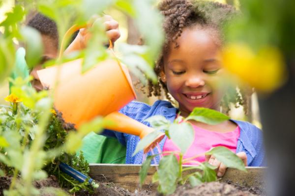 child gardening with yellow watering can 