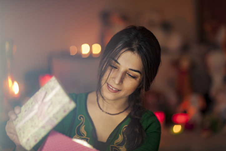 West Asian woman opens Christmas gift