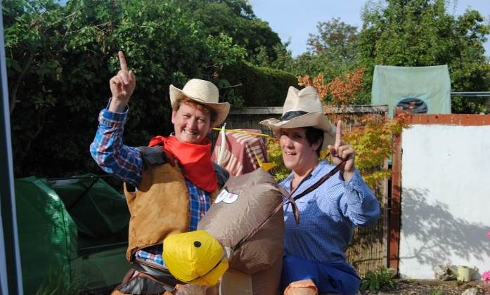 Two people dressed as cowboys with an inflatable horse