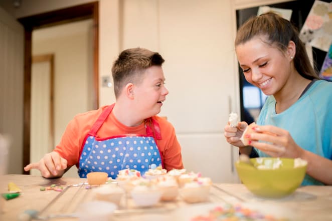 Boy with Down's syndrome baking cakes with family member