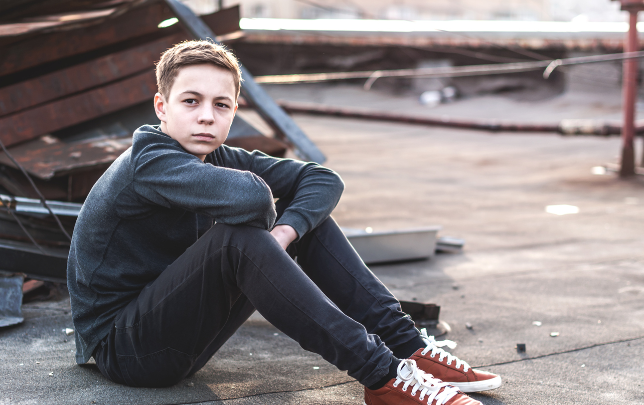 Pensive teenager sitting on the roof of the house