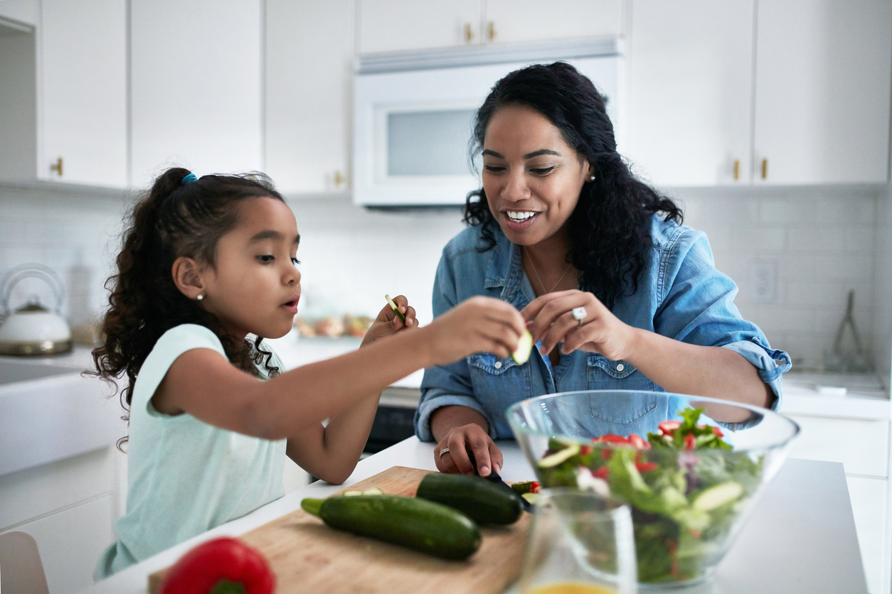 Girl learning to prepare meal from her foster carer