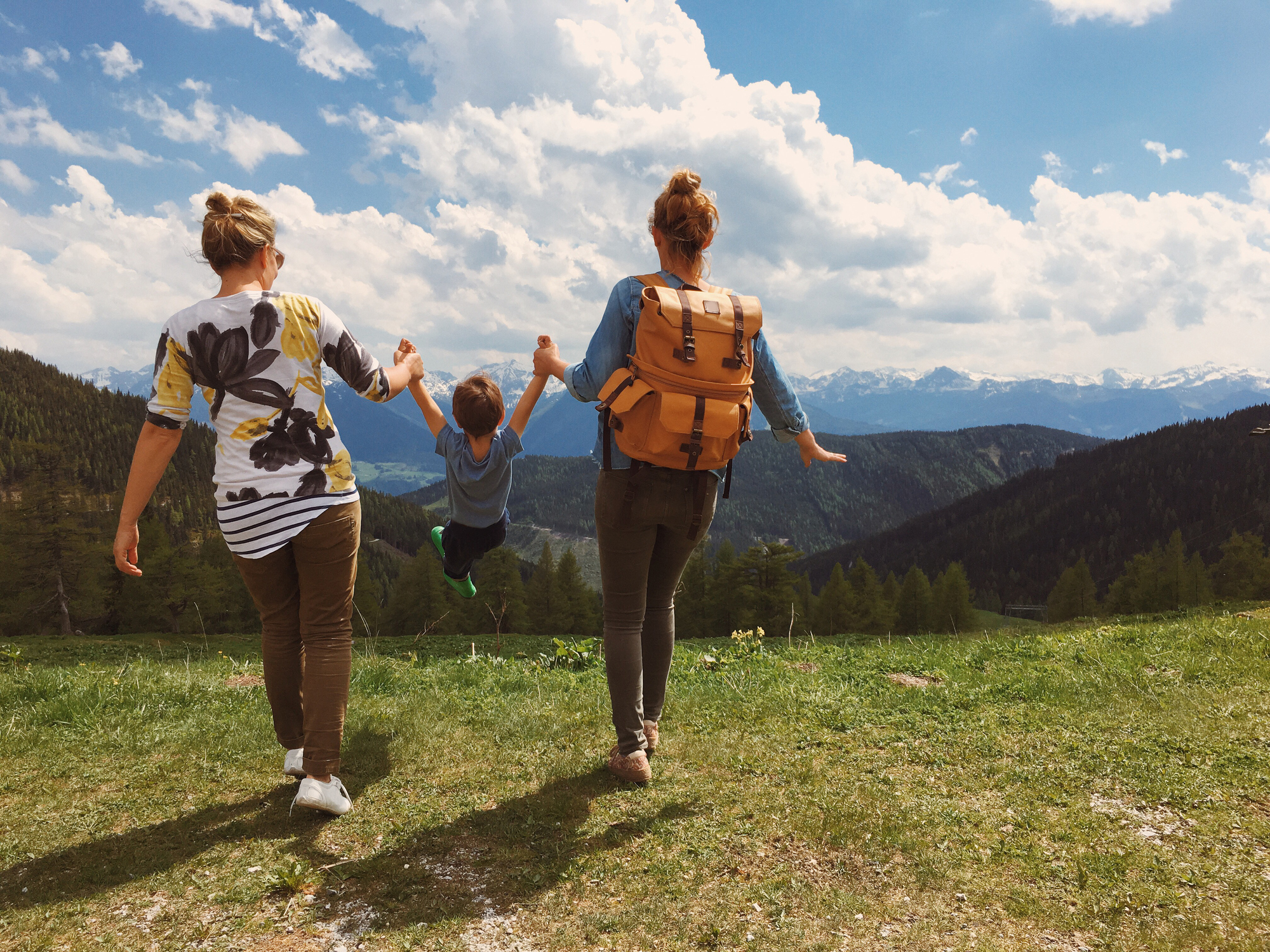 Young female foster care couple with boy walking on hill