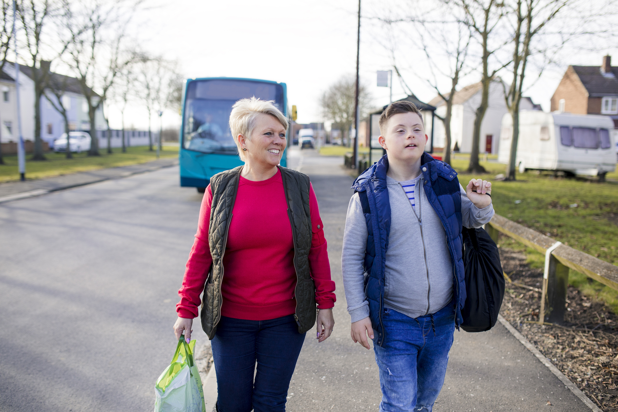 Female foster carer and male foster child getting off bus