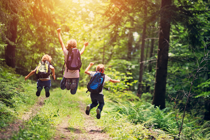 Three children jumping in woods