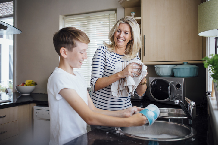 Women washing pots with young foster child