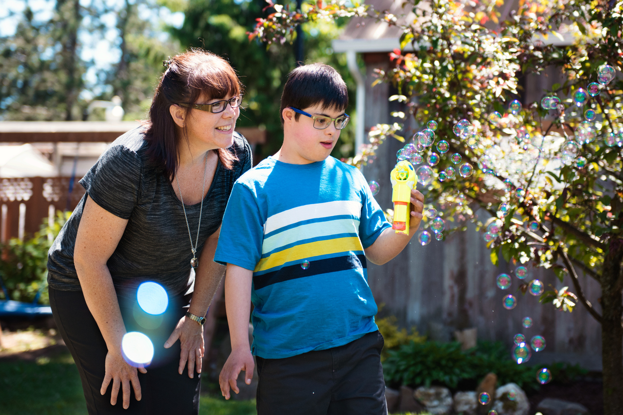 Mother and autistic son playing with bubbles in garden