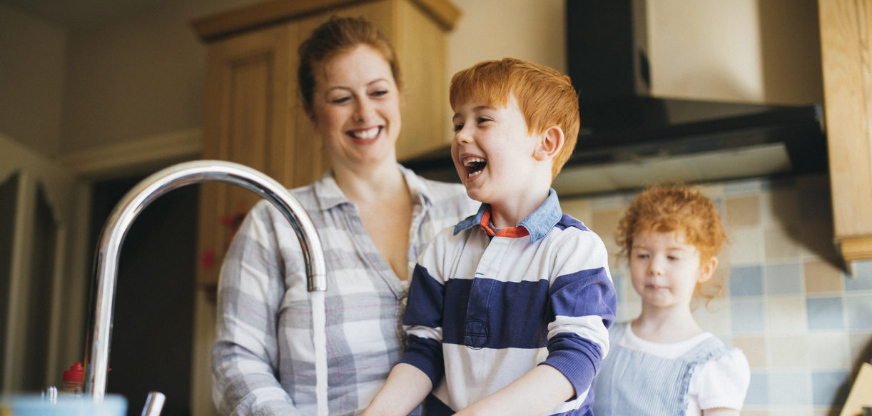 Two foster children and their foster carer washing the dishes