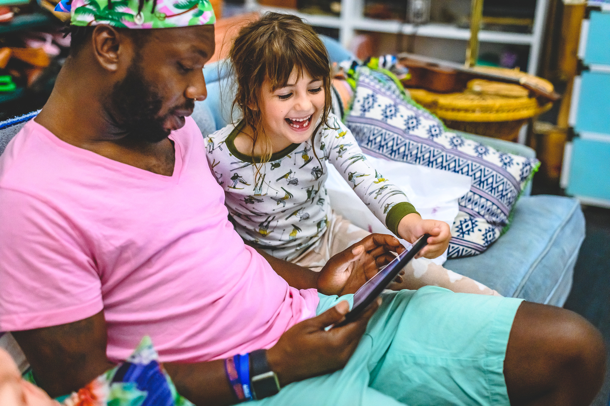 Foster carer and foster child use a digital tablet at home together