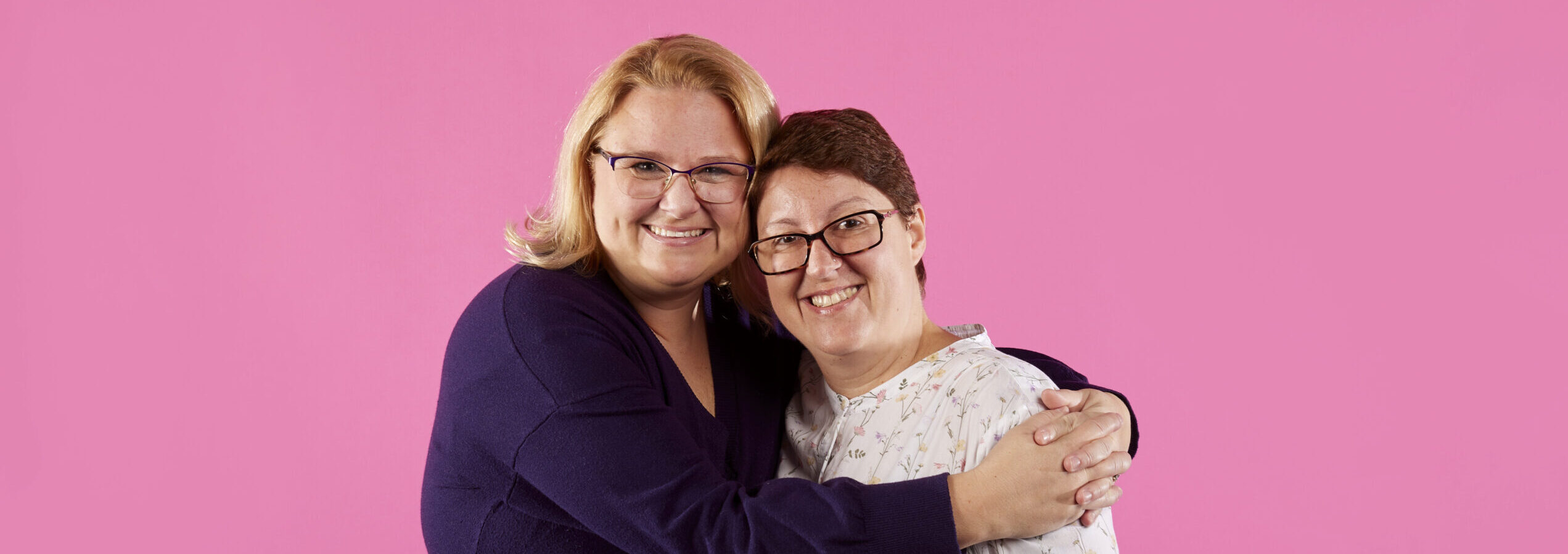Two same sex female foster carers hugging and smiling