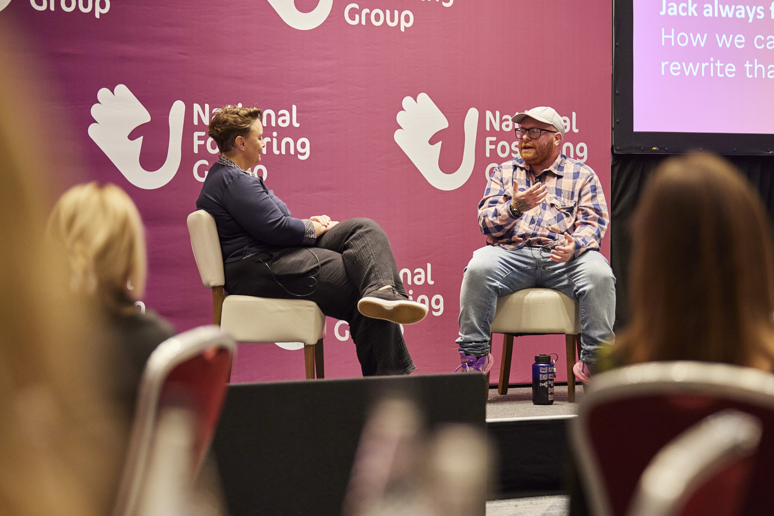Two people sitting on a stage at a conference, discussing a topic.
